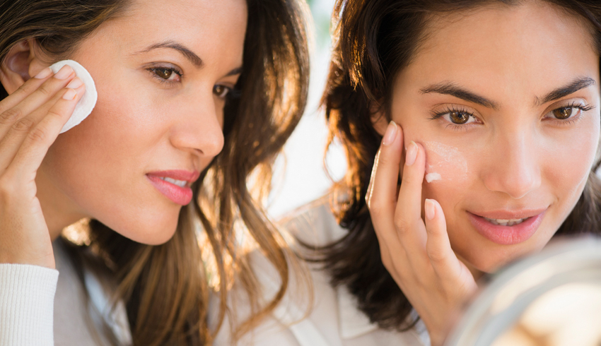 Two women look into a makeup mirror as they practice their skin care routine.